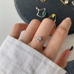 Detailed close-up of a silver chain ring with an oval zircon on a model finger