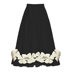 Detail of a black A-line skirt featuring large white 3D floral appliques and flared hem