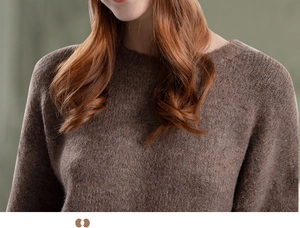 Macro detail of the plush knit texture and ribbed crew neck of the brown winter sweater
