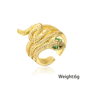 Macro detail of 18K gold snake ring with green stone eyes and zircon pavé texture