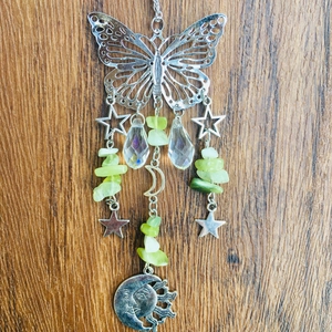 Detailed view of silver butterfly suncatcher with sun, moon stars and green gemstones