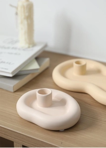 Close-up of matte ceramic candle holders in cloud shapes on a wooden table decoration