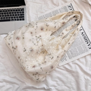 Detail of embroidered tulle tote bag with floral patterns and a decorative bow accent