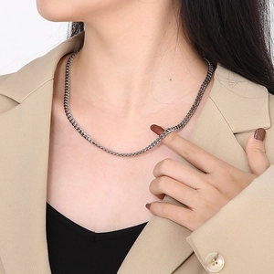 Close-up of a silver cuban link chain necklace worn by a model in a beige suit