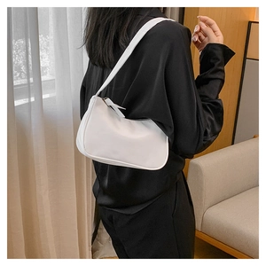 Close-up of a minimalist white crescent baguette bag with smooth faux leather and slim strap
