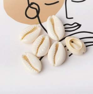 Macro view of natural white cowrie shells for DIY jewelry making on art background