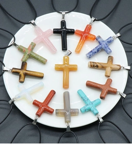 Macro view of thirteen colorful natural stone cross pendants with black wax cords