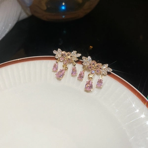 Dettaglio degli orecchini a nappa con zirconi rosa appesi a un piatto in ceramica bianca