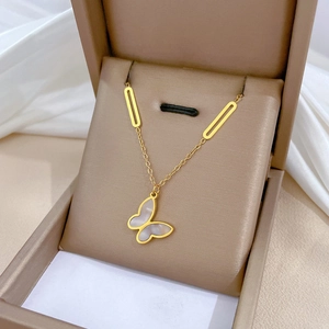 Minimalist gold butterfly necklace with mother of pearl inlay on elegant silk background