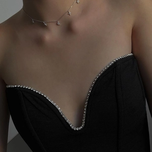 Close-up of black tube top dress with rhinestone trim and silver star pendant necklace