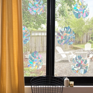 Rainbow prism window decal in monstera leaf shape creating colorful light on glass