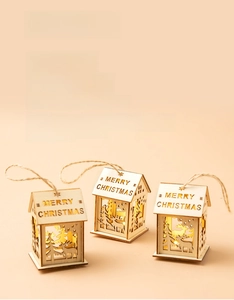 Detailed view of three laser-cut wooden Christmas house ornaments with warm LED lighting