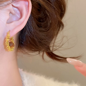 Close-up of vintage resin hoop earring with gold textured metal and amber bead details
