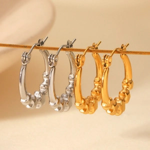 Polished star-shaped gold and silver hoop earrings hanging on a thin metal chain