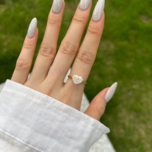 Close-up of heart-shaped cut zircon ring in gold finish on female hand outdoors