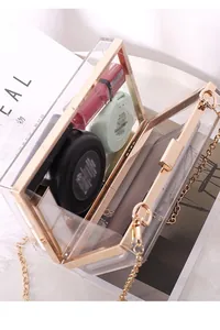 Detail view of transparent acrylic clutch showing spacious interior and gold metal frame