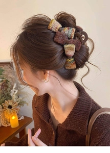Détail de la pince à cheveux à nœud en tweed montrant la texture et la fixation robuste