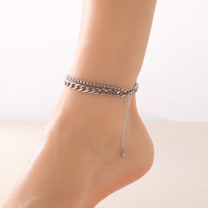 Double-layered silver anklet with snake chain and flat Cuban links worn on ankle