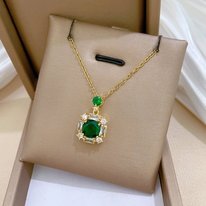 Macro detail of luxury square emerald pendant with zircon accents on gold chain necklace