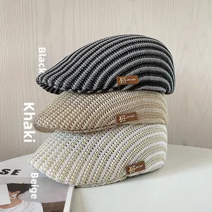 Esposizione verticale di tre cappellini in maglia traforata in nero, kaki e beige
