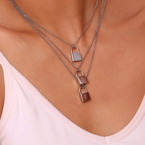 Detail of triple-layer stainless steel necklace with gothic letter padlock pendants