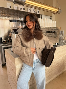 Detail of warm beige winter jacket featuring a plush dark brown faux fur collar and soft texture