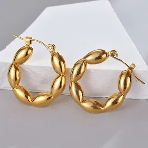 Polished gold stainless steel segmented hoop earrings on white stone display