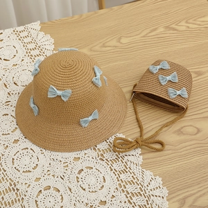 Detail of straw hat and matching crossbody bag with light blue lace bow for girls