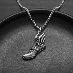 Gros plan d'un collier avec pendentif basket à ailes argentées sur un plateau sombre