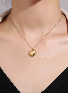 Close-up of a 3D heart-shaped gold pendant on a minimalist chain worn by a model