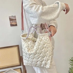 Quilted floral handbag with pink adjustable strap shown from side view on model