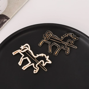 Chic gold-tone horse shaped hair clips with black and white enamel fill on a black tray