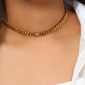 Close-up of a gold Cuban link chain necklace with a rectangular pink gemstone pendant
