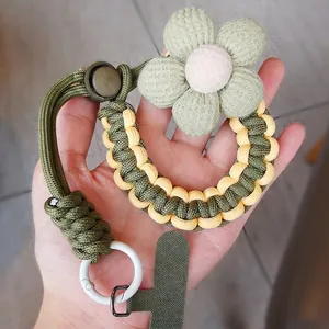 Handmade woven phone wrist strap in green and yellow with a plush sponge flower charm