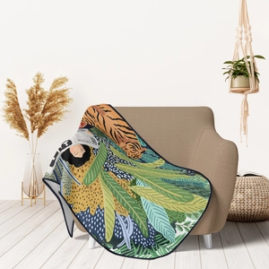 Artistic tropical leaf flannel blanket with woman and tiger illustration draped on sofa