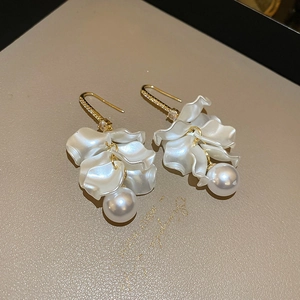Macro detail of petal earrings with gold hooks, small zircons, and dangling pearls