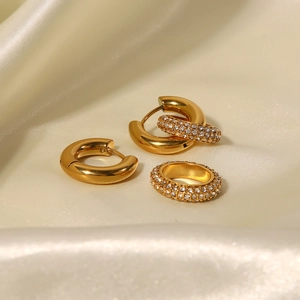 Detailed view of gold earrings and rhinestone ear cuff set on elegant beige silk fabric