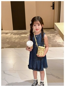 Little girl wearing a yellow bucket bag with cherry prints in a bright hotel corridor
