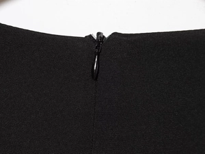 Détail de la fermeture éclair invisible sur la robe courte plissée noire de précision
