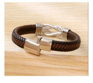 Close-up of woven leather punk bracelet with silver magnetic clasp on wood surface