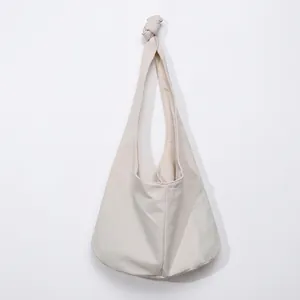 Detail of minimalist cream canvas hobo bag showing the decorative shoulder strap knot