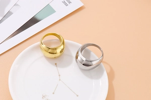 Close-up of gold and silver polished thick dome stainless steel rings on a ceramic dish