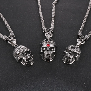 Detailed macro of vintage punk skull pendants with red crystal crown and silver steel chains