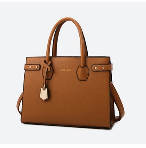 Detail of brown litchi pattern handbag with dual handles and golden fashion pendant