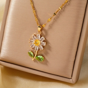 Gros plan d'un collier pendentif tournesol doré avec zircon jaune et feuilles vertes