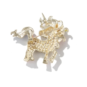 Macro shot of gold-toned unicorn brooch showing textured metallic finish and pin clasp