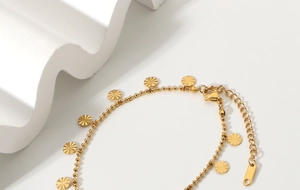 Macro detail of 18K gold plated beaded anklet with sunburst textured disc pendants