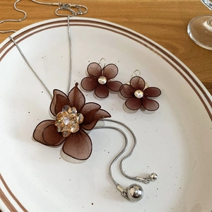 Detailed view of brown mesh flower necklace and earrings set with sparkling crystals