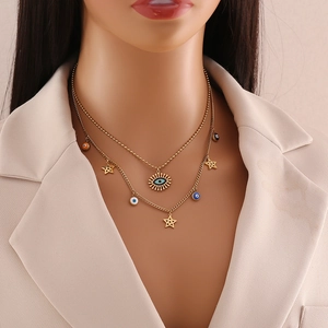 Close-up of gold double-layer necklace with blue evil eye and hollow star charms
