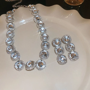 Sparkling silver flower necklace and earring set with round crystals on a white plate